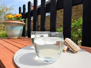 A glass of water on a white plate, a slice of cake, and a potted plant with yellow flowers on a wooden table. - 1 Bed in Oakham (oc-60672) (Oakham)