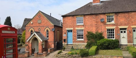 A red telephone booth and a brick building with a blue door.