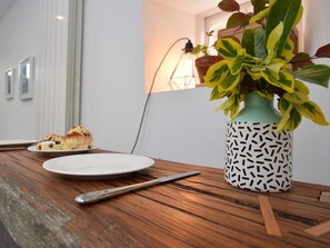A wooden table with a plate of food, a spoon, and a potted plant with variegated leaves. - 1 Bed in Oakham (oc-60672) (Oakham)