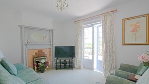 Ein Wohnzimmer mit Kamin, Fernseher und zwei grünen Sesseln.