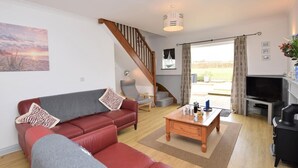 Ein Wohnzimmer mit einem roten Sofa, einem Holztisch, einem Fernseher und einer Treppe.