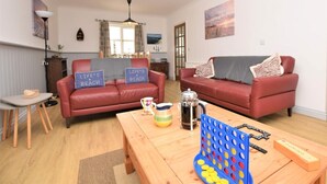 Ein Wohnzimmer mit zwei roten Ledersofas, einem Holztisch und einem Gesellschaftsspiel.