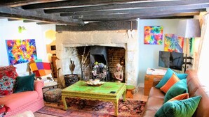 A cozy living room with a fireplace, a sofa, a coffee table, and colorful artwork. - 4 Bed in Godshill (oc-ic034) (Godshill)