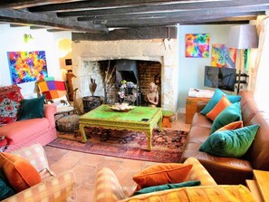 Ein gemütliches Wohnzimmer mit Kamin, einer Couch, einem Couchtisch und farbenfroher Kunst.