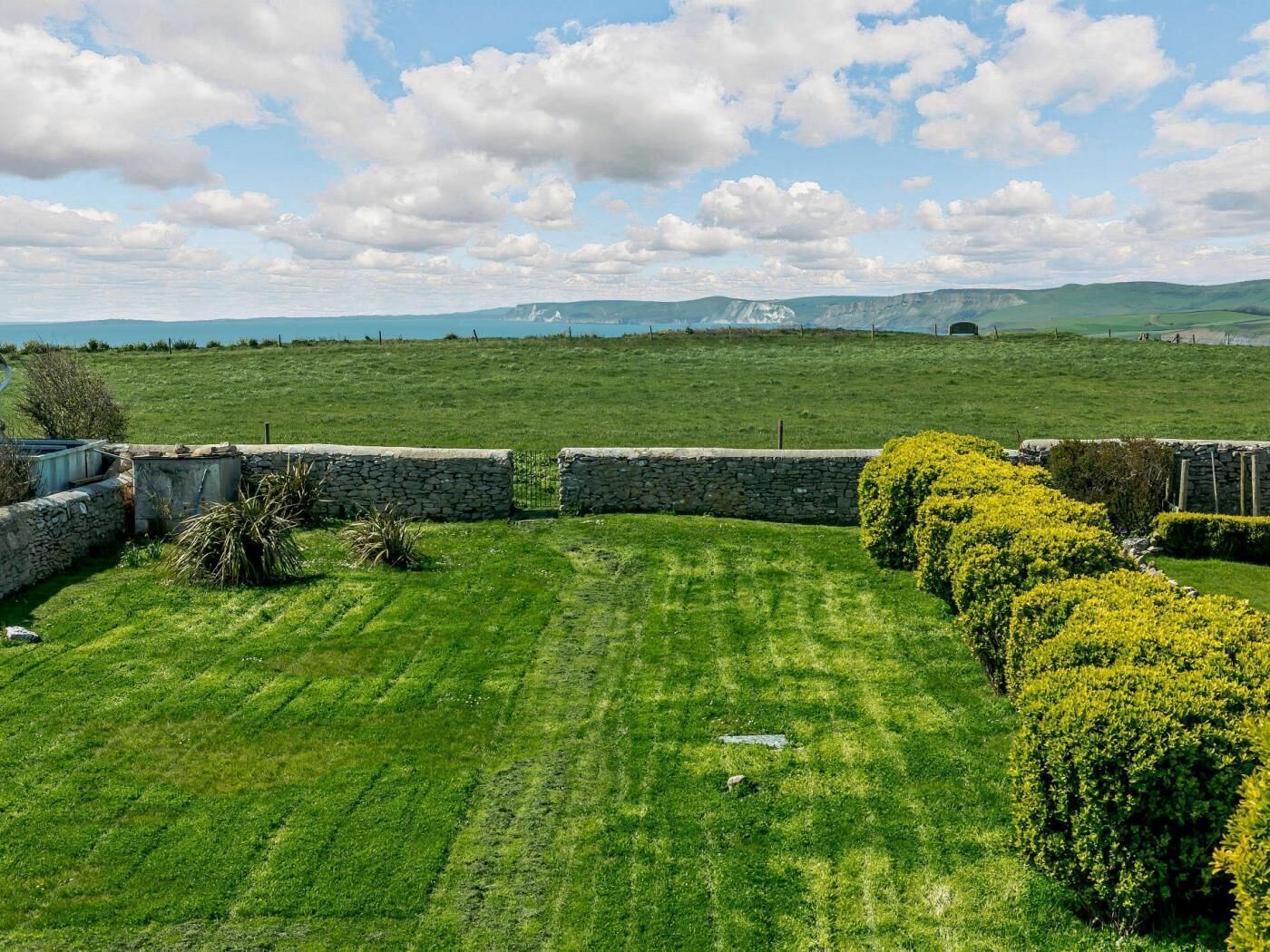 A grassy field with stone walls and a clear sky.