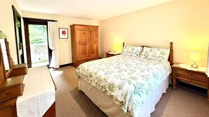 Una camera da letto con un letto, comodini, un armadio e una porta che dà su un balcone.