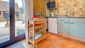Una cucina con mobili in legno, un forno a microonde, un lavandino e un piccolo frigorifero.