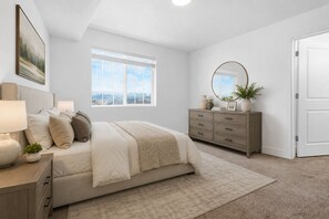 Un dormitorio con cama, mesitas de noche, cómoda, espejo y ventana.