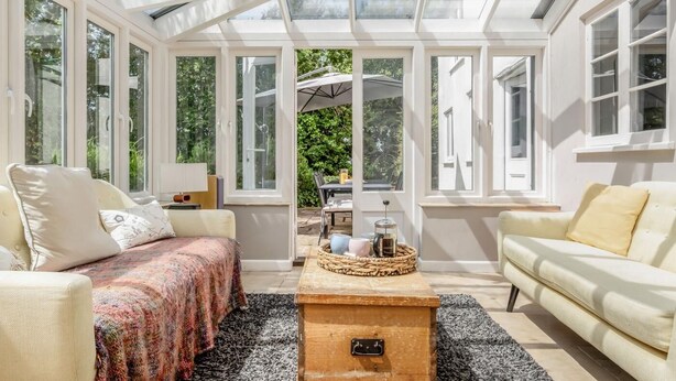 Una habitación soleada con techo alto, ventanas amplias y vistas al exterior.