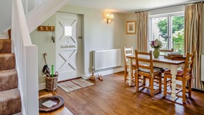 A wooden staircase, a dining area with a table and chairs, a radiator, and a door with a sign. - 1 Bed in Cowes (oc-ic084) (Cowes)