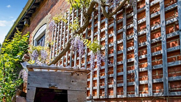 A brick building with a wooden pergola and a wooden bench. - 1 Bed in Cowes (oc-ic084) (Cowes)