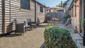 A wooden cabin with a patio area featuring outdoor furniture and a table. - 2 Bed in Godshill (oc-ic085) (Godshill)