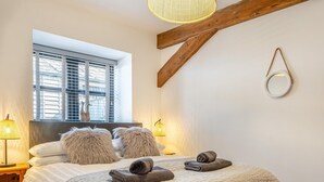 Ein Schlafzimmer mit einem Bett, zwei Lampen, einem Fenster und einem Holzbalken.