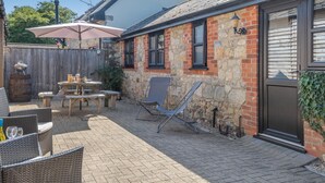 A patio with outdoor furniture, a barbecue grill, and a stone building with a door. - 2 Bed in Godshill (oc-ic085) (Godshill)
