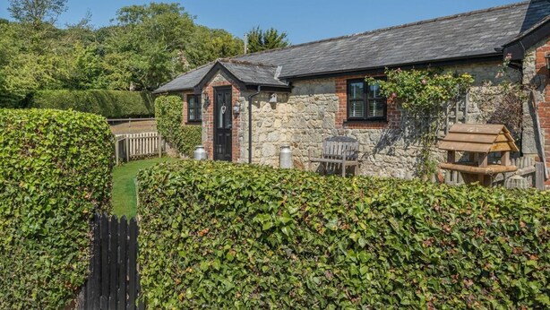 A stone cottage with a sloped roof, a wooden door, and a small porch area. - 2 Bed in Godshill (oc-ic085) (Godshill)