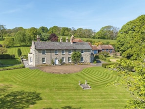 A large stone house with a well-maintained lawn and a clear view of the surrounding countryside. - 1 Bed in Godshill (oc-ic052) (Godshill)