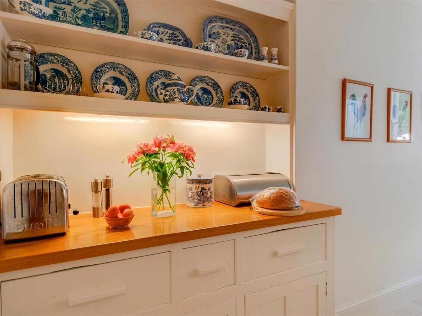 A kitchen with a wooden countertop, a toaster, a vase with flowers, and blue and white plates on shelves.