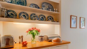 A kitchen with a wooden countertop, a toaster, a vase with flowers, and blue and white plates on shelves. - 1 Bed in Godshill (oc-ic052) (Godshill)