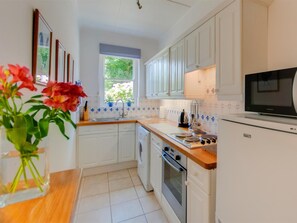 A kitchen with white cabinets, a microwave, a sink, and a window. - 1 Bed in Godshill (oc-ic052) (Godshill)