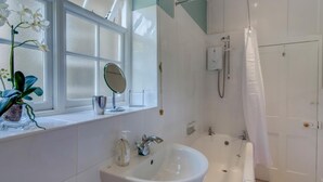A bathroom with a sink, mirror, shower, and window with plants. - 1 Bed in Godshill (oc-ic052) (Godshill)