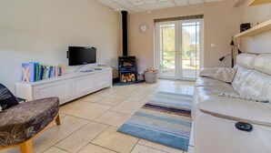 Ein Wohnzimmer mit einer Couch, einem Fernseher, einem Kamin und einem Bücherregal.