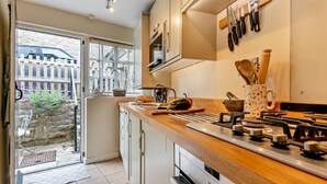 Una cocina moderna con estufa a gas, encimera de madera y vistas a la ciudad a través del ventanal.