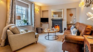 Una sala de estar con chimenea, un sofá, una mesa de centro y una televisión.