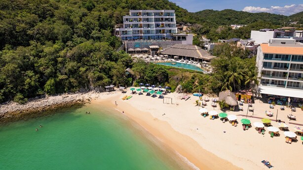 Ein Hotel mit Pool, Strand und üppiger Vegetation.