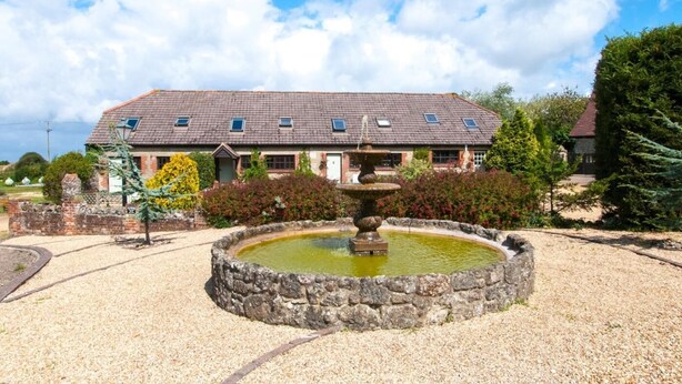 A building with a tiled roof, a stone fountain, and a gravel courtyard. - 2 Bed in Godshill (oc-ic106) (Godshill)
