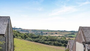 A rural landscape with a clear sky, rolling hills, and a distant view of a village. - 2 Bed in Godshill (oc-ic106) (Godshill)