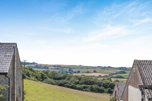 A rural landscape with a clear sky, rolling hills, and a distant view of a village. - 2 Bed in Godshill (oc-ic106) (Godshill)