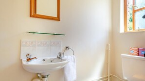 A bathroom with a white sink, mirror, and toilet. There is a towel hanging on the wall and a window with a view of greenery. - 2 Bed in Godshill (oc-ic106) (Godshill)