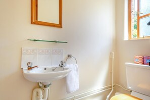 A bathroom with a white sink, mirror, and toilet. There is a towel hanging on the wall and a window with a view of greenery. - 2 Bed in Godshill (oc-ic106) (Godshill)
