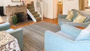 Ein Wohnzimmer mit Kamin, einer Treppe, einer Couch und einem Essbereich.