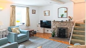 Ein Wohnzimmer mit Sofa, Fernseher, Kamin und Treppe.