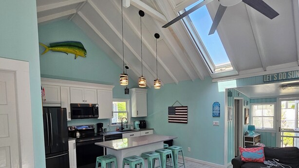 Una cucina moderna con isola centrale, sgabelli da bar e una ventola a soffitto.