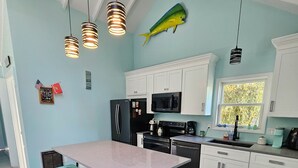 Una cucina con isola centrale, sgabelli da bar, una decorazione a forma di pesce e lampade a sospensione.