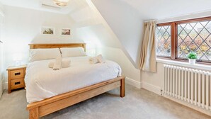 A bedroom with a wooden bed, a nightstand, a radiator, and a window with a view. - 2 Bed in Alnwick (oc-93093) (Lemmington Hall)