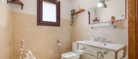 Une salle de bain avec des toilettes, un lavabo, un miroir et une fenêtre.