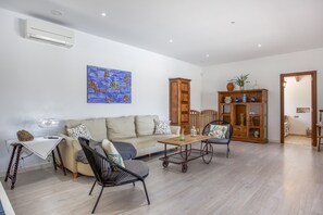 A living room with a sofa, chairs, a coffee table, a cabinet, and a painting on the wall.
