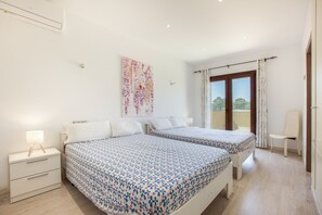 Habitación de hotel con dos camas, una mesita de noche, una lámpara, un cuadro en la pared y vistas a través de la ventana.