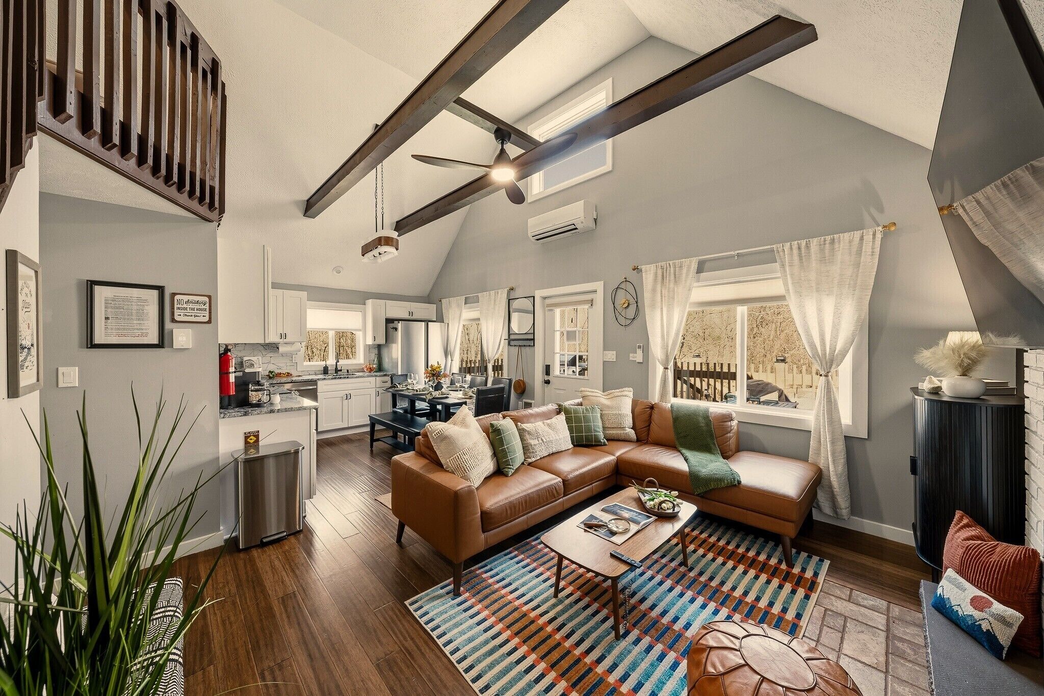 A spacious living area with a large brown leather sofa, a coffee table, and a colorful rug.