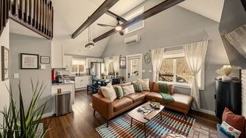 A spacious living area with a large brown leather sofa, a coffee table, and a colorful rug.