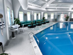 An indoor swimming pool with a lounge area, seating, and a clear poolside area. - GameRoom•FirePit•Grill•KidsFriendly•9 min Kalahari (Long Pond)