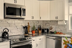 A modern kitchen with white cabinets, a stainless steel microwave, a gas stove, and a dishwasher. - GameRoom•FirePit•Grill•KidsFriendly•9 min Kalahari (Long Pond)