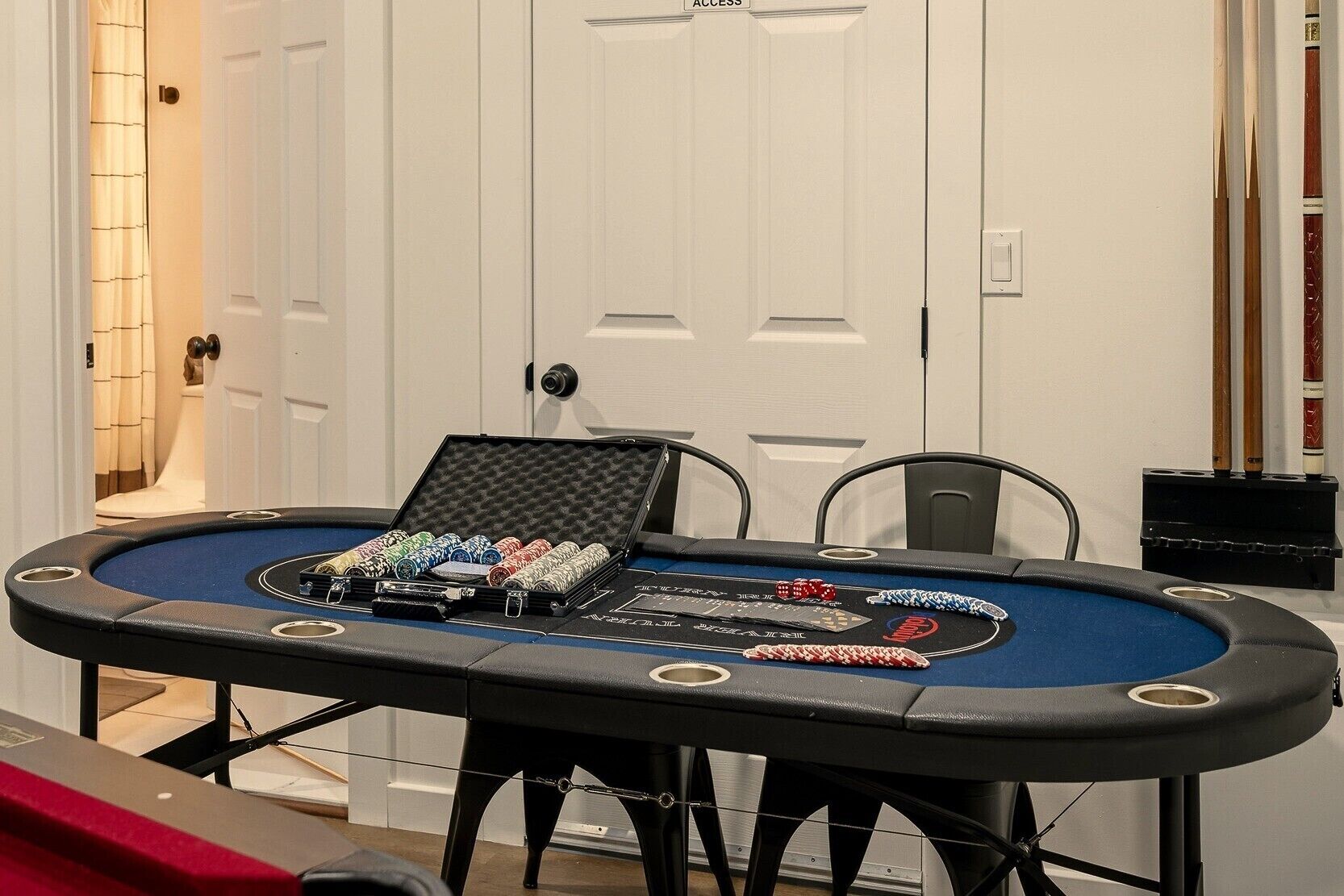 A poker table with chips and cards, a door with an 'ACCESS' sign, and a pool table in the background.