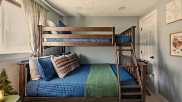 Een stapelbed met houten frame, een groene deken en blauw beddengoed.
