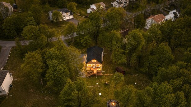 Vista aérea de um bairro residencial com uma casa que possui um amplo deque e interior bem iluminado.