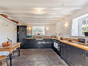 Una cocina con suelo de piedra, armarios de madera, una ventana con vistas y un tostador ProCook.