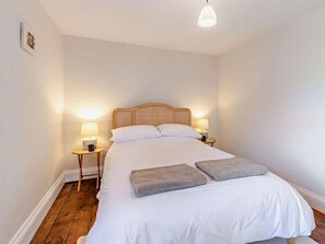 Une chambre à coucher avec un lit, deux tables de chevet, une commode, une lampe et un tableau au mur.